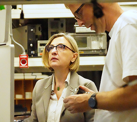 Professor Laura Marcu with a short blond hair looking up. Next to her is Julien Bec who is looking at small object he is holding in his hands.